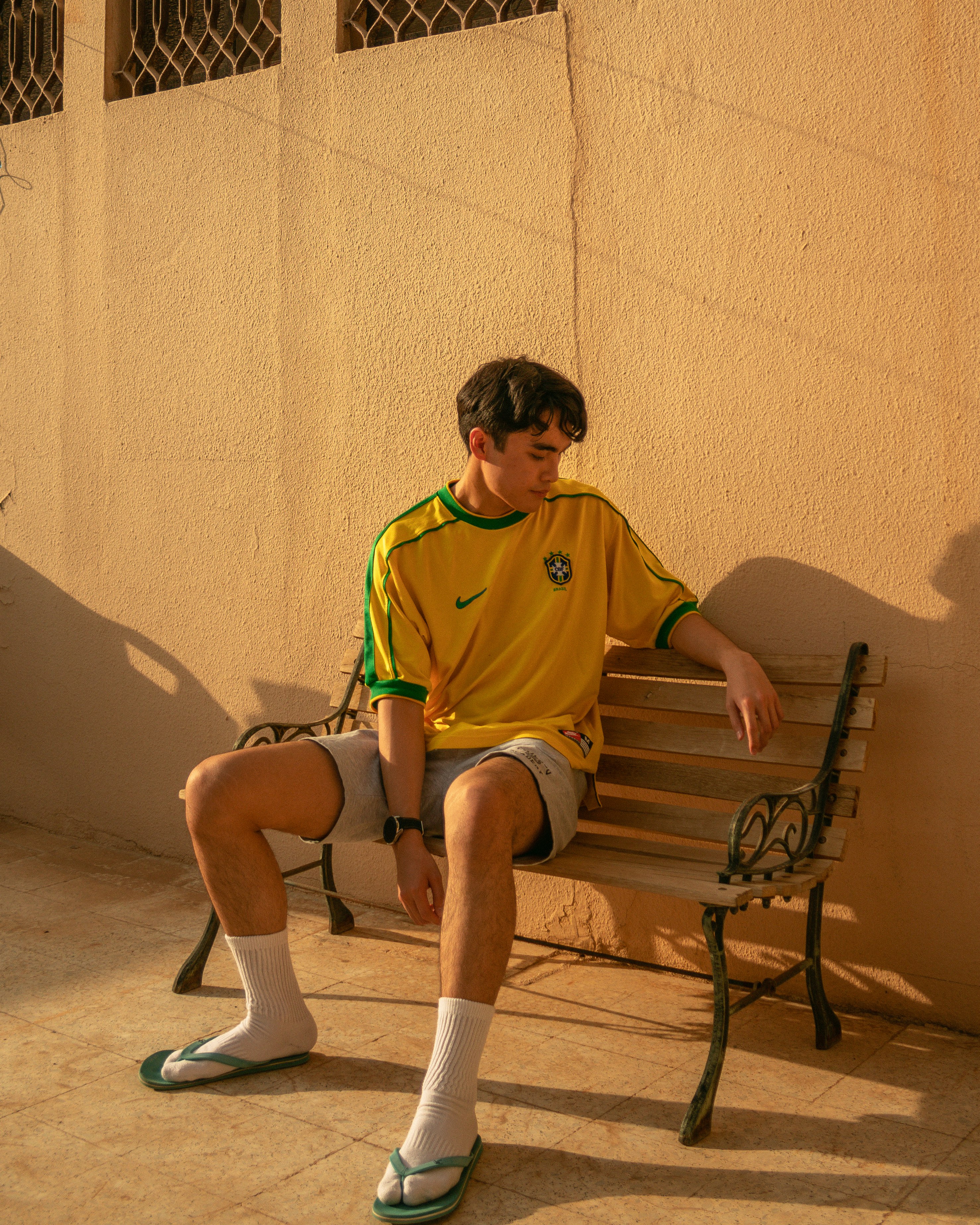 boy in green nike crew neck t-shirt sitting on brown wooden bench